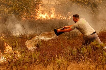 Un hombre arroja agua para sofocar las llamas del incendio en el municipio de Odemira, Portugal, este lunes.