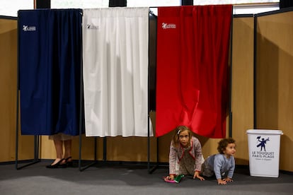 Romy y Jude, de 8 y 2 años, juegan en una cabina electoral en  Le Touquet-Paris-Plage (Francia).