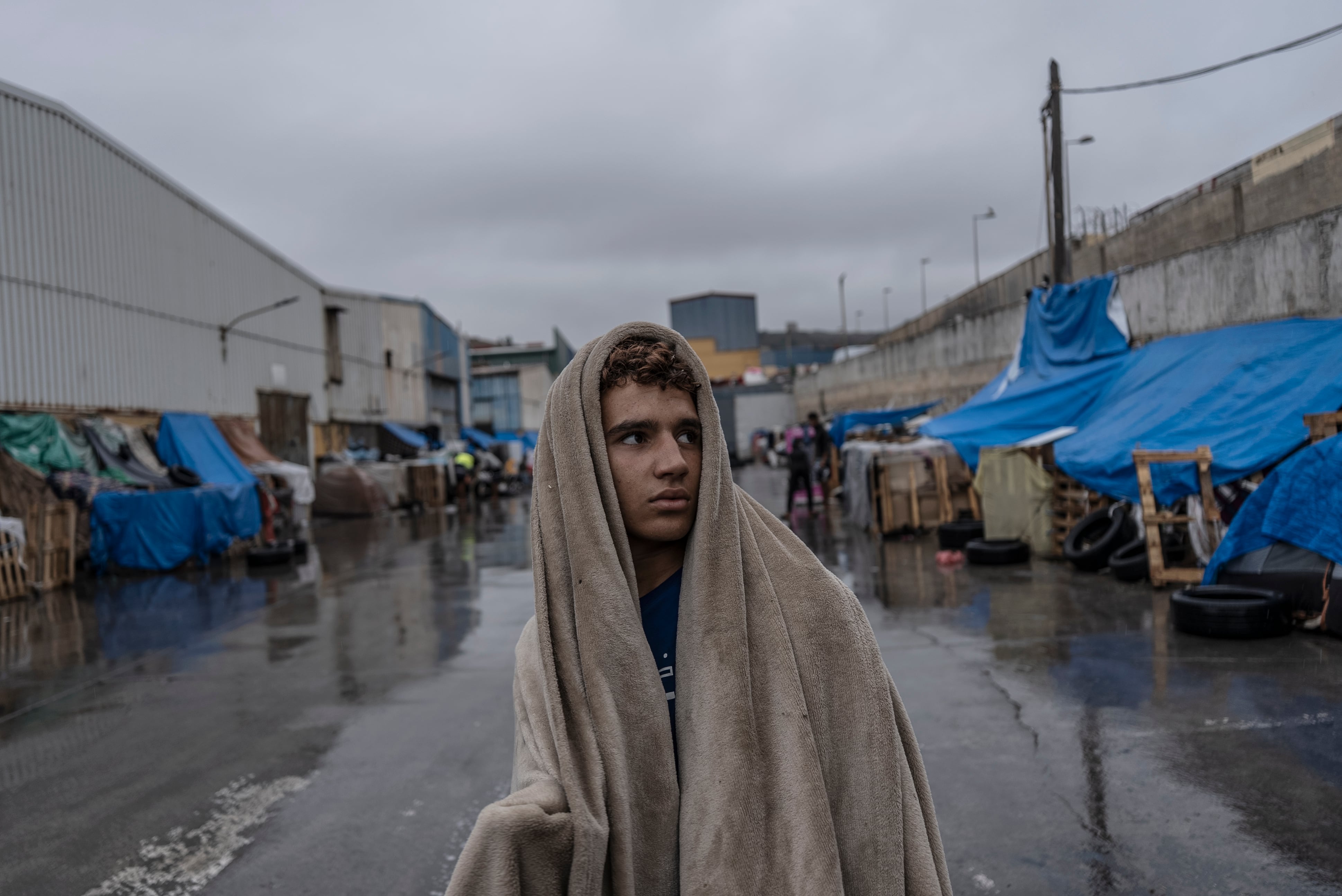 Un joven se arropa con una manta tras pasar la noche mojado debido a las filtraciones de la lluvia en su chabola, situada en un polígono industrial cercano a la frontera de El Tarajal en Ceuta, España, el 27 de septiembre.