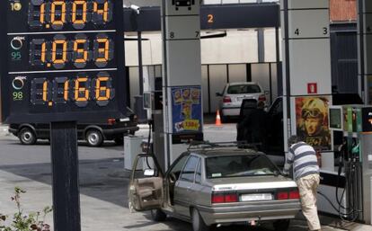 Un hombre reposta carburante en su coche en una estación de servicio.