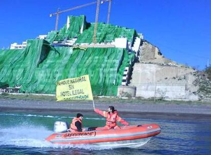 Una zodiac de Greenpeace con la pancarta "Parque natural sin hotel ilegal" protesta contra el hotel El Algarrobico al fondo semicubierto