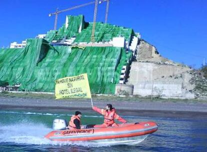 Una zodiac de Greenpeace con la pancarta "Parque natural sin hotel ilegal" protesta contra el hotel El Algarrobico al fondo semicubierto