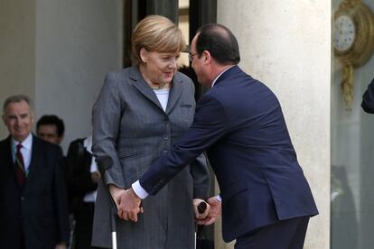 El presidente francés Francois Hollande acude a ayudar a la canciller alemana Angela Merkel con sus muletas a su llegada a una reunión de gabinete conjunta franco-alemana en el Palacio del Elíseo en París.