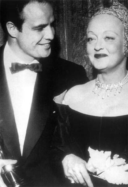 Marlon Brando, con el galardón al mejor actor por <i>La ley del silencio,</i> en 1955, junto a Bette Davis, quien le hizo entrega del premio.