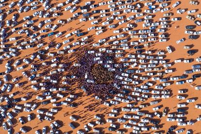Una vista aérea, que muestra automóviles y personas que rodean a un grupo de camellos, en medio de las arenas del desierto, durante el festival anual de camellos 'King Abdulaziz' en Rumah, a unos 160 kilómetros al este de Riad (Arabia Saudí),