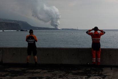 Dos trabajadores de Salvamento Marítimo observan la columna de gas que se genera cuando la lava entra en contacto con el mar, este martes. 