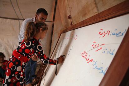 Una niña escribe en la pizarra durante una clase.