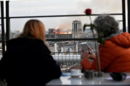 Dues dones observen l'incendi a la catedral de Notre-Dame des d'un edifici proper.