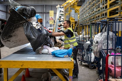 Un operario descarga ropa en la planta de tratamiento textil de Koopera Mediterránea en Ribarroja de Turia (Valencia).