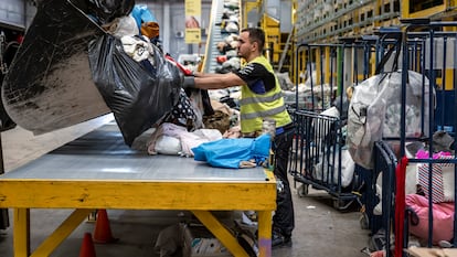 Un operario descarga ropa en la planta de tratamiento textil de Koopera Mediterránea en Ribarroja de Turia (Valencia).