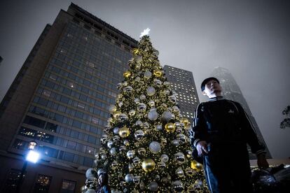 Un hombre junto a un árbol de Navidad en Hong Kong, China.