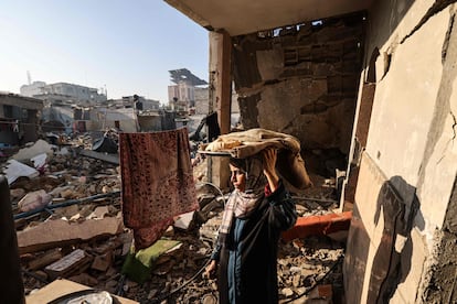 Una mujer lleva pan en mitad de su casa destrozada en Rafah, al sur de la franja de Gaza, este lunes 18 de diciembre.  