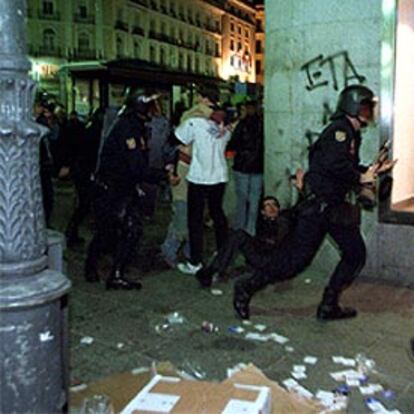 Varios policías persiguen a algunos manifestantes en las inmediaciones de la Puerta del Sol.