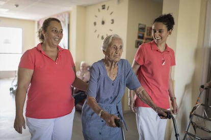 Martina Hernández, de 95 años, asistida por dos auxiliares en la residencia Servitrés de Santa Cruz de Retamar, Toledo.