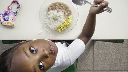Una alumna almuerza un plato de arroz y legumbres en el comedor de su colegio, que sigue ofreciendo menús diarios a los niños de familias más vulnerables.