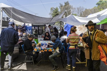 Un grupo de personas comen en puestos improvisados al exterior del Mercado San Cosme, al norte de la capital mexicana. Este mercado fue el primero en incendiarse el 22 de diciembre del año pasado, 188 locales fueron afectados.