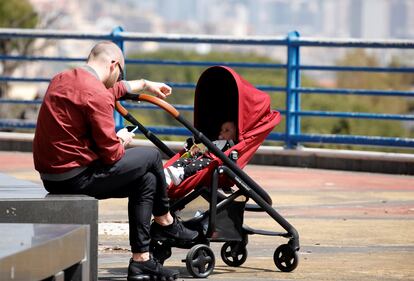 A man checks his mobile phone next to a baby in a stroller as the spread of coronavirus disease (COVID-19) continues, in Naples, Italy April 19, 2020. REUTERS/Ciro De Luca