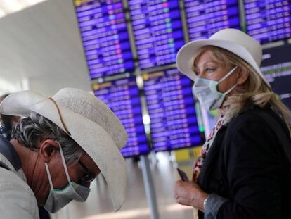 Dos viajeros con mascarillas esperan su vuelo en el aeropuerto de El Prat.