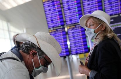 Dos viajeros con mascarillas esperan su vuelo en el aeropuerto de El Prat.