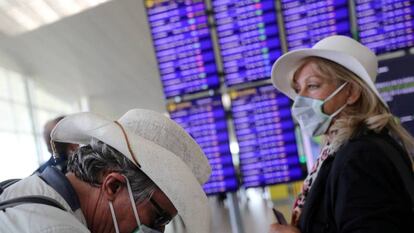 Dos viajeros con mascarillas esperan su vuelo en el aeropuerto de El Prat. / NACHO DOCE (REUTERS)