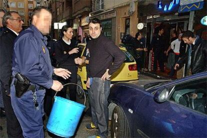 Un policía sostiene el cubo en el que se encontraba una recien nacida hallada en un bar de copas de Zaragoza.