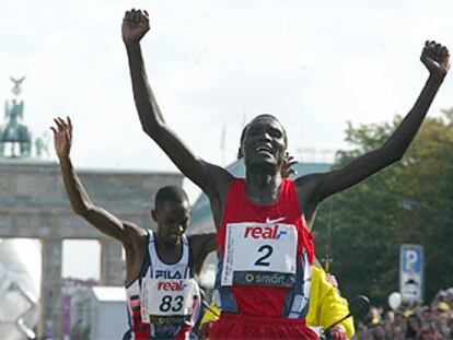 Paul Tergat atraviesa la meta del maratón de Berlín seguido por Sammy Korir y con la Puerta de Brandenburgo al fondo.