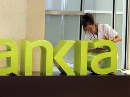 Una operaria limpia el logo de Bankia. EFE/Archivo