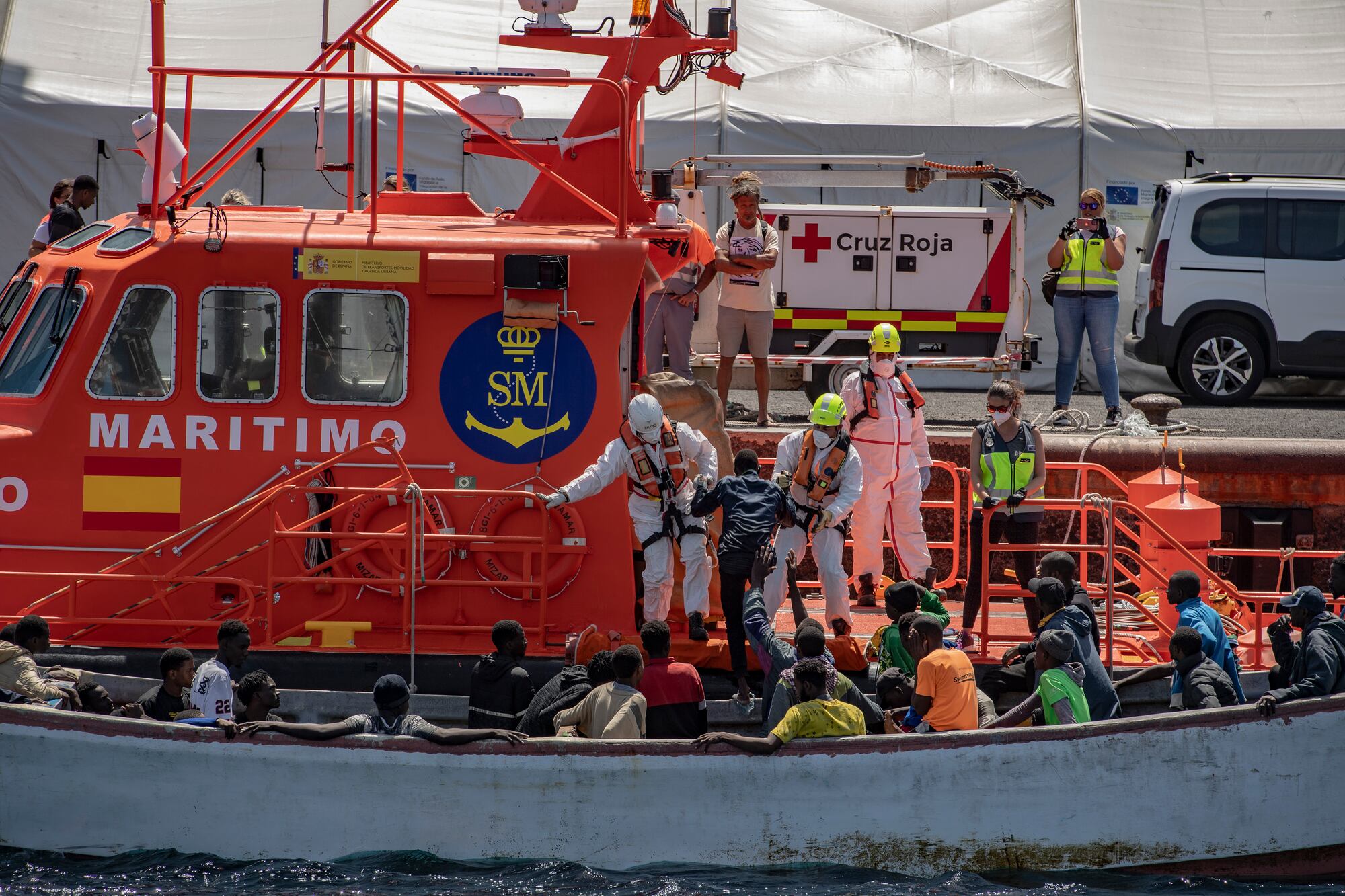 Miembros de los equipos de emergencias ayudan a desembarcar a varios migrantes de un cayuco, en el Puerto de La Restinga, a 9 de septiembre de 2024, en El Hierro, Canarias (España). Un cayuco con 81 migrantes de origen subsahariano a bordo, entre ellos tres mujeres y tres menores, ha sido interceptado este lunes, 9 de septiembre, en aguas al suroeste de El Hierro. La embarcación fue detectada por el radar del SIVE a unas 8,5 millas al suroeste de la isla y a su encuentro partió la Salvamar Mízar, que acompañó al cayuco en condiciones de seguridad hasta el puerto de La Restinga.
09 SEPTIEMBRE 2024
Antonio Sempere / Europa Press
09/09/2024