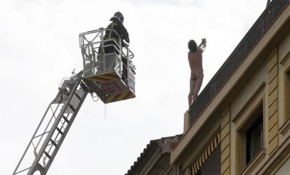 Los bomberos intentan rescatar al hombre subido a la cornisa de la azotea.