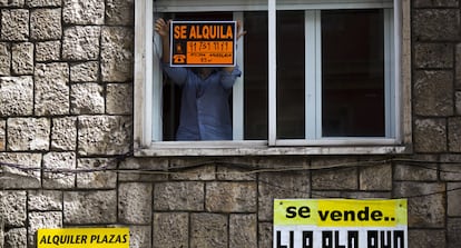 Un hombre coloca un cartel de alquiler en una vivienda de Madrid.