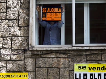 Un hombre coloca un cartel de alquiler en una vivienda de Madrid.