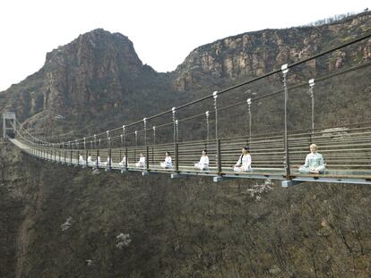 Un grupo de mujeres practica yoga en un puente colgante de cristal como forma de atraer turistas en Fuxishan (China).