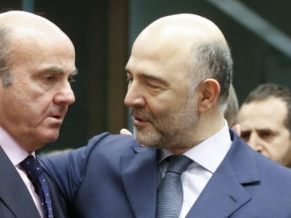 El ministro español de Economía, Luis de Guindos (i) conversa con el comisario europeo de Asuntos Económicos, Pierre Moscovici, durante una reunión de los responsables de Economía y Finanzas de la zona del euro en la sede del Consejo Europeo en Bruselas el 14 de enero de 2016.