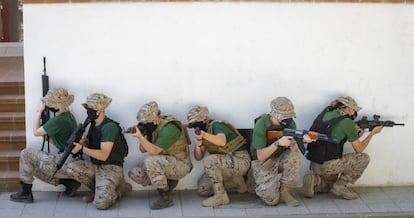 Simulación del asalto a una vivienda. Los jóvenes llevan uniforme militar: pantalón mimetizado, camiseta verde oliva y chambergo.