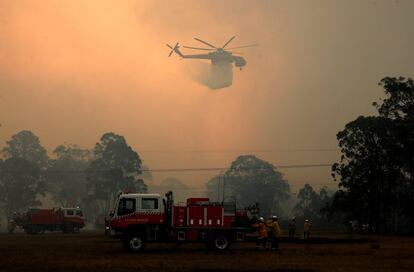 Un helicóptero de bomberos suelta agua para apagar el incendio que arrasa el entorno natural de la ciudad australiana de Newcastle.