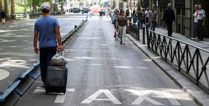 Un turista pasea por el carril Taxi del Paseo del Prado de Madrid durante la huelga de Taxistas.