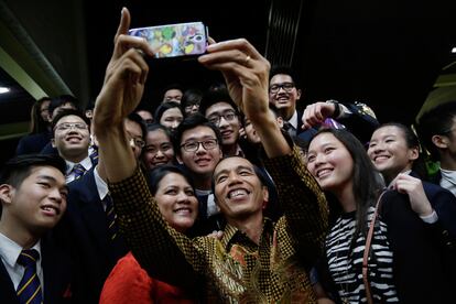 El presidente indonesio Joko Widodo, se hace un selfie, junto a un grupo de estudiantes recién graduados, entre ellos, su hijo menor, Kaesang Pangarep, en Singapore.