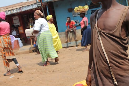 La vida cotidiana en las calles de Sierra Leona antes del estado de emergencia para evitar el contagio de la covid-19. Un niño carga un bidón de agua mientras las mujeres en el fondo ofrecen frutas a precios módicos en las cercanías de Kissy Dockyard, Freetown.