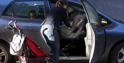 Una mujer coloca a su hijo en una silla portabebés.
