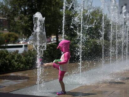 Una nena es refresca en una font, a Barcelona.