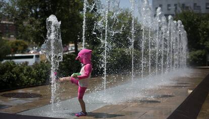 Una nena es refresca en una font, a Barcelona.