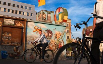 Ciclistas paseando por la East Side Gallery de Berlín al atardecer.