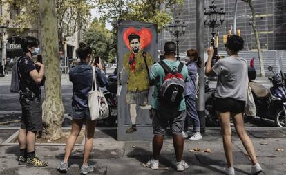Varios viandantes toman fotografías de una obra del artista TVBoy que representa a Messi, el 29 de agosto en Barcelona.