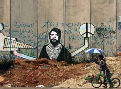 Un joven palestino pasa con su bicicleta junto a un puesto de control del muro entre Jerusalén y Ramala.