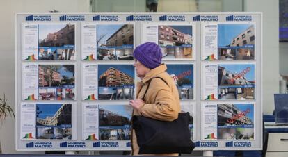 Una mujer pasa por delante de una inmobiliaria.