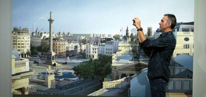 Un hombre saca una foto en la exposición 'Hiperrealismo 1967-2013' ante la pintura 'Mirando atrás hacia Richmond House' (2011), de Ben Johnson.
