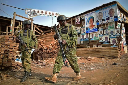 Soldados ugandeses caminan delante de carteles electorales en Kampala en el día de las votaciones a la presidencia de Uganda.