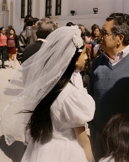 San Pedro Sacatepéquez, San Marcos; 2019.
Una niña con un hermoso vestido de primera comunión está junto a su padre frente a la iglesia. Su vestimenta indica sutilmente riqueza en medio de las tradiciones de las tierras altas. Mientras tanto, la fe católica profundamente arraigada compite con las iglesias evangélicas por la influencia en el lugar. Esta imagen resume el delicado equilibrio entre la tradición, el lujo y la dinámica religiosa que configura la vida en las tierras altas de Guatemala.