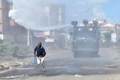 TOPSHOT - A protester runs away as police use water cannon to disperse demonstrators on November 28, 2017 during demonstrations at Umoja suburb of capital Nairobi, after police denied permission for main opposition, National Super Alliance (NASA) leader to hold a rally concurrently with the inauguration of Kenyan President.
President Uhuru Kenyatta vowed to be the leader of all Kenyans and work to unite the country after a bruising and drawn out election process that ended with his swearing-in. / AFP PHOTO / TONY KARUMBA