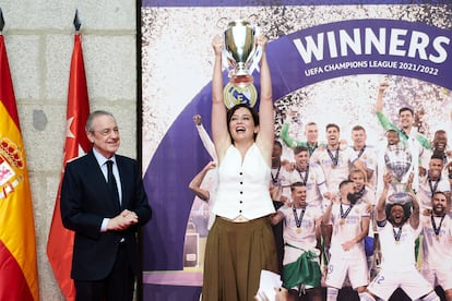 La presidenta de la Comunidad de Madrid, Isabel Díaz Ayuso, levanta la miniréplica de la Copa de Europa que le acaba de entregar el presidente del Real Madrid, Florentino Pérez. 